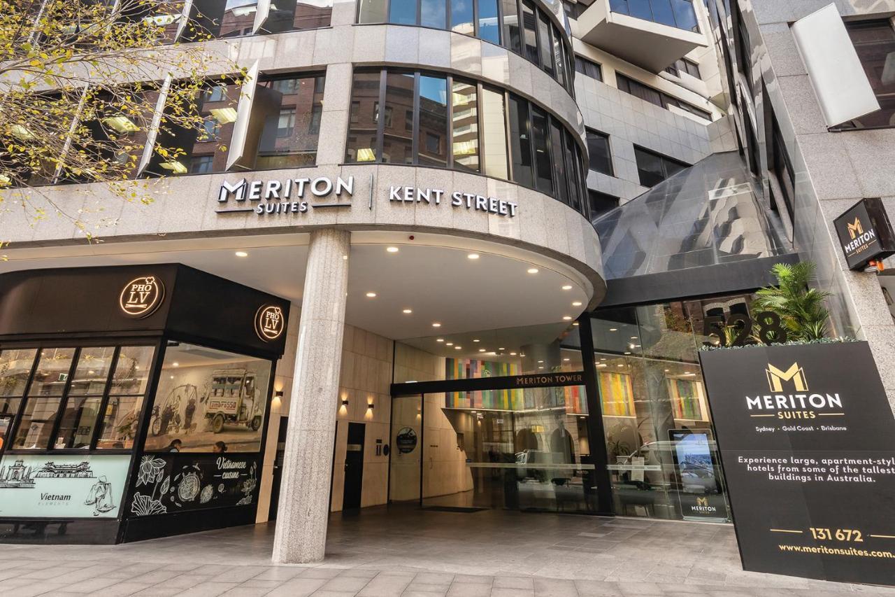 Meriton Suites Kent Street, Sydney Exterior photo The photo shows the entrance of the Meriton Suites located on Kent Street. The building features a modern design with a glass facade and prominent signage displaying the name "Meriton Suites." There is also a large sign near the entrance with additio